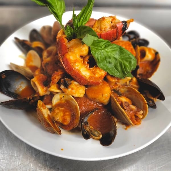 LouCas's Italian seafood dish with lobster, mussels, clams, and calamari in red sauce, garnished with basil.