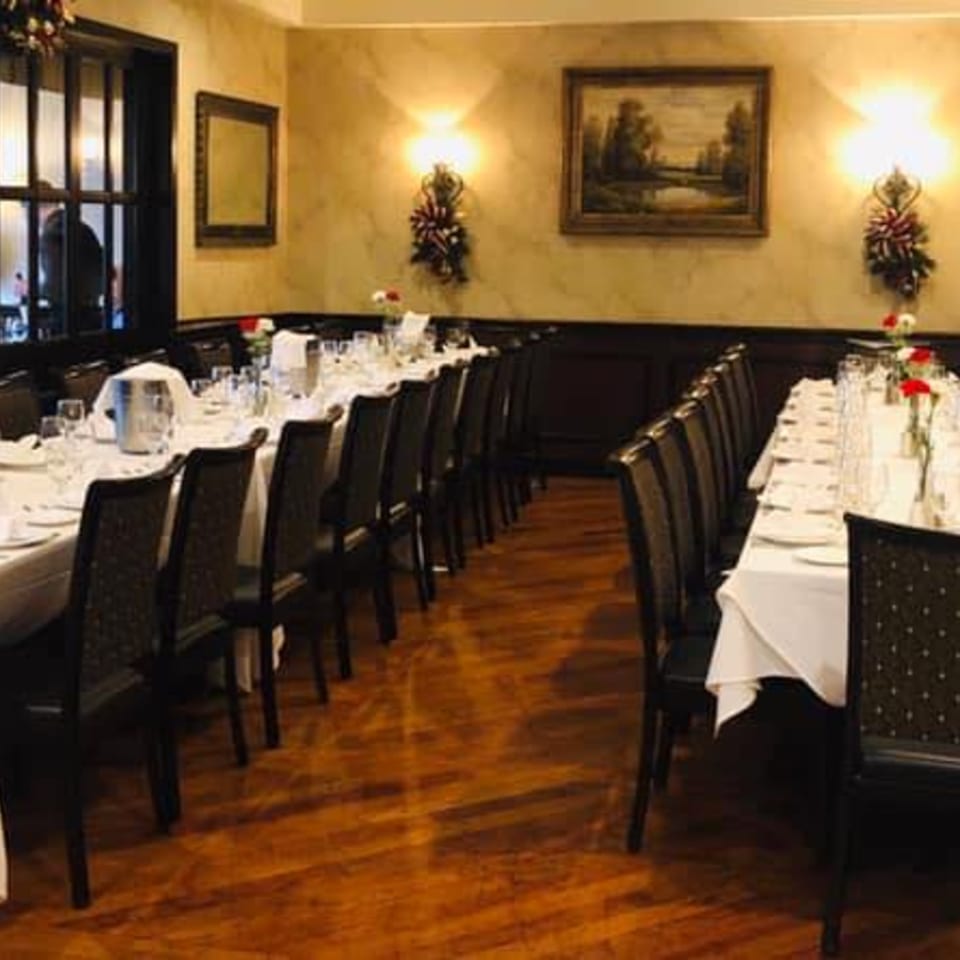 LouCas dining room with long tables set for a banquet, dark chairs, and warm lighting.
